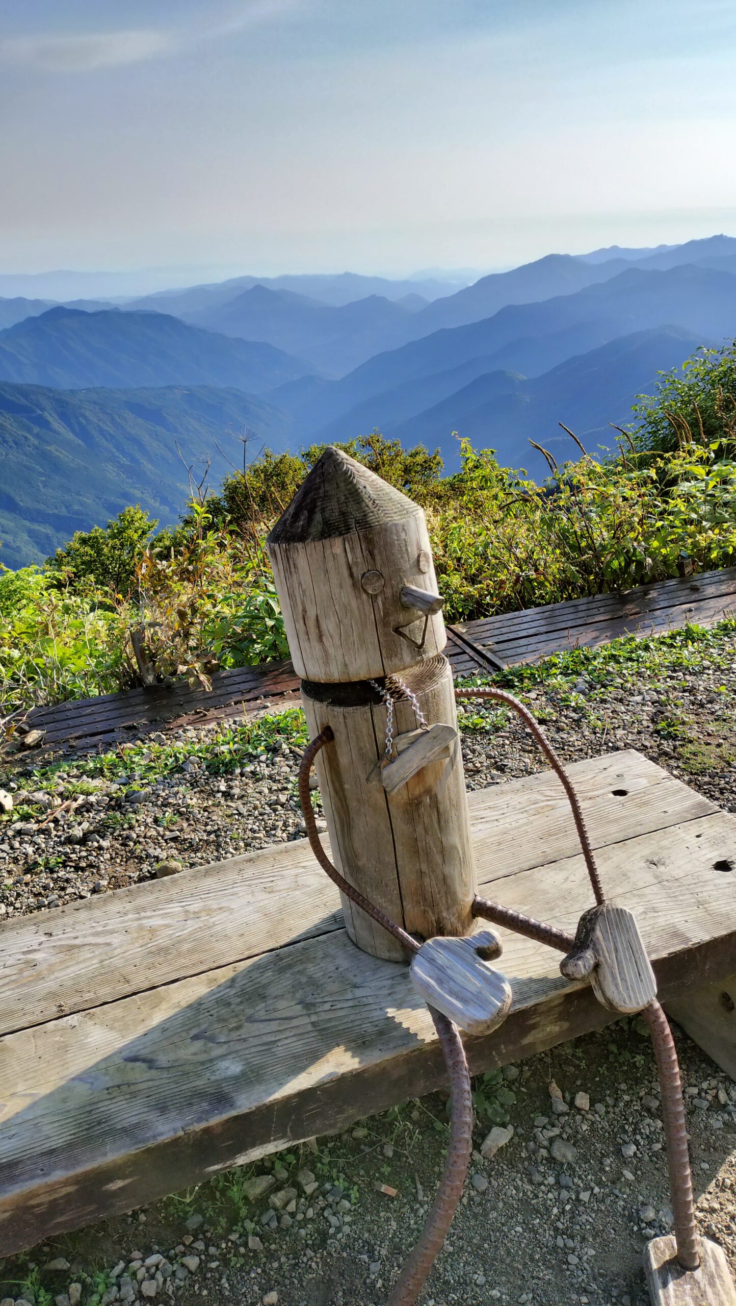剣山の山々を背に、木のベンチに座る木製の人形
